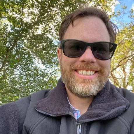 files/1762414705-imgi_1_selfie-of-a-middle-aged-man-sitting-under-trees.webp